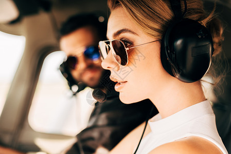 坐在飞机舱男飞行员旁边的太阳镜和耳机上吸引着有吸引力背景图片