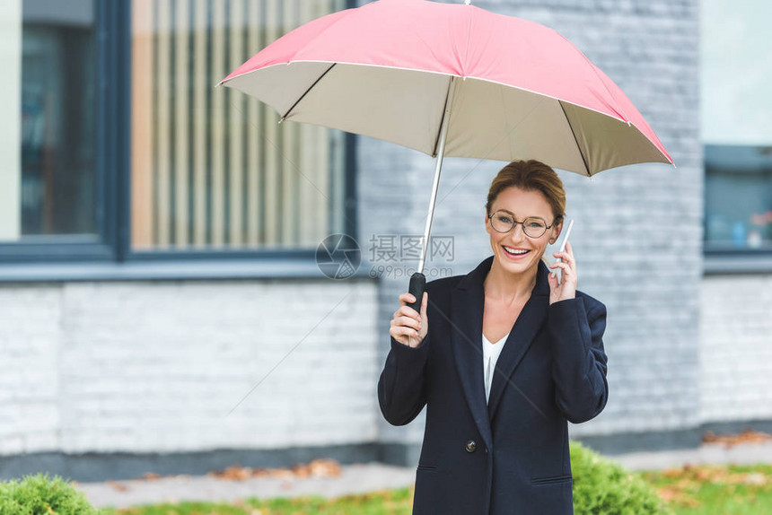 穿着黑色大衣的笑着成熟女人带着雨伞用图片