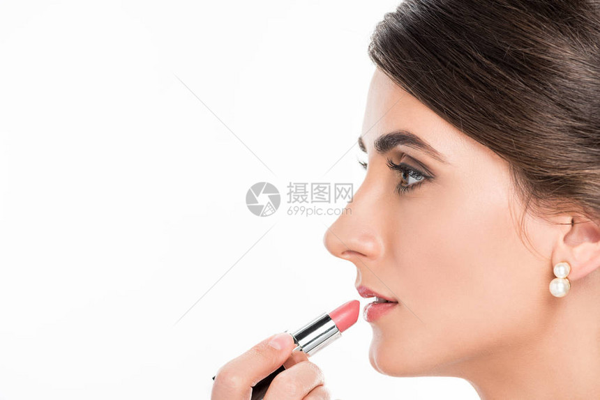 将口红涂在模型嘴唇上的化妝艺术家的侧面视图图片