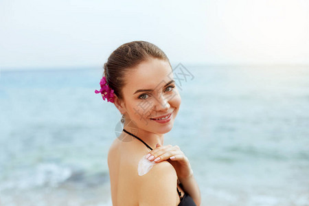 女人在晒黑的肩膀上涂抹防晒霜皮肤护理防晒背部使用防晒图片