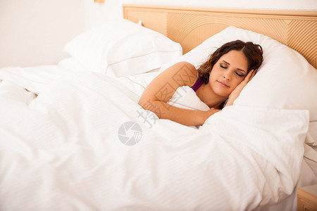 可爱的年轻女子睡在酒店床上做个好图片