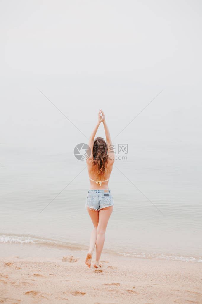 女孩背面的景色在沙滩上伸图片