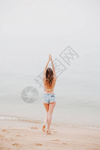 女孩背面的景色在沙滩上伸背景图片