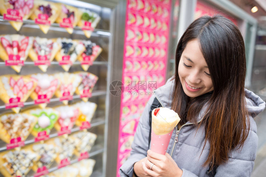 亚洲女人在竹下街享用奶油可丽饼图片