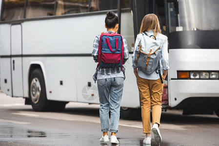 在城市街道上背包走在公共汽车附近图片