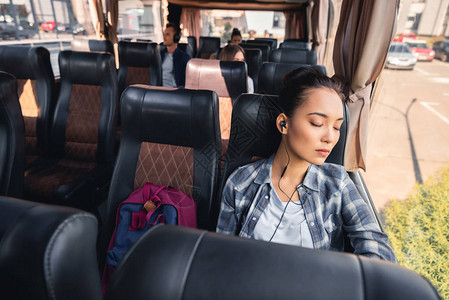 乘公车旅行时年青女在耳听器中睡图片
