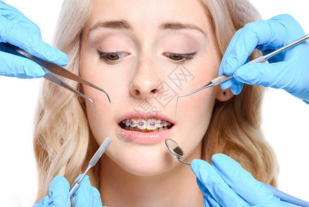 一名戴牙套手举起牙医工具贴近脸部的有图片