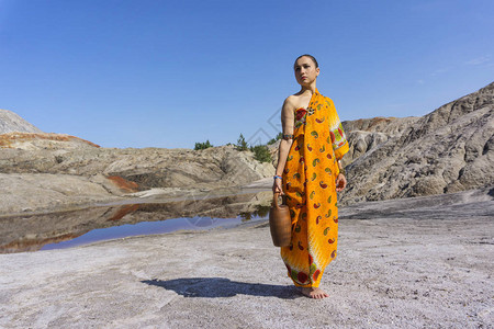 身着民族服装的青年女子在沙漠地貌用陶瓷图片