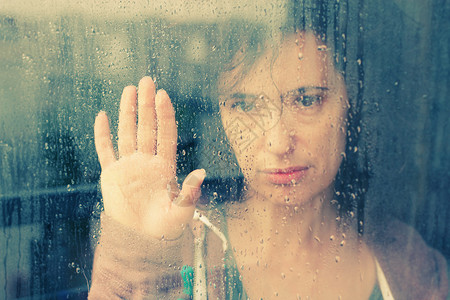 美丽的女人站在窗前带着雨图片