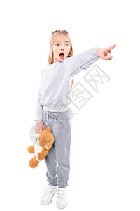 惊吓的小女孩拿着泰迪熊用手指着她在图片