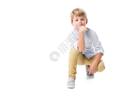 可爱的小男孩跪在地上看镜头孤立在图片