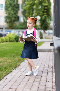 忧郁的红发女学生拿着书望着外面的学校图片