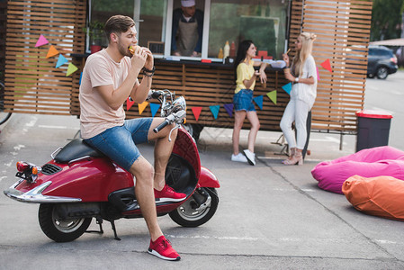 男人吃汉堡坐着摩托车在图片