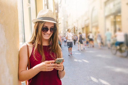 身戴太阳眼镜和帽子手机在城市街图片