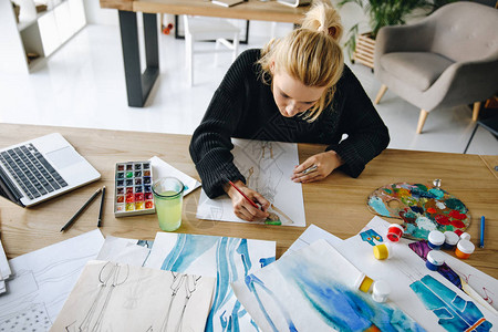 年轻女时装设计师在工作场所绘制水彩图片