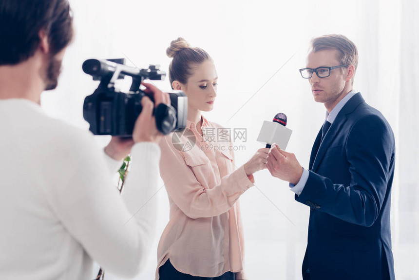 身戴眼镜的英俊商人给记者和办公室摄像员进行视频采访图片