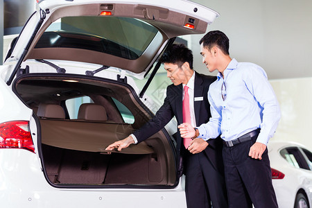 亚洲经销商的汽车销售员向顾客展示SU图片
