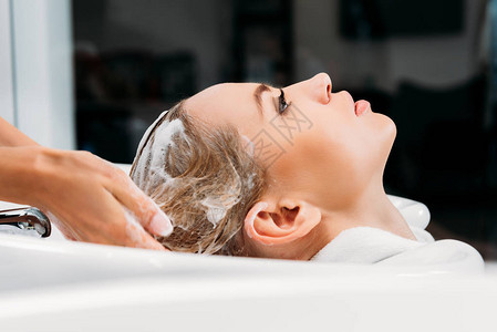 美发师用洗发水为顾客洗头的侧视图图片