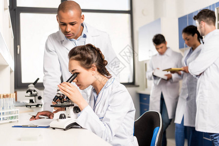 女科学家在现代生物实验室与显微镜一起工作期间图片