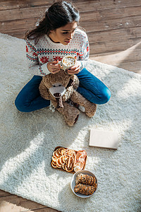 妇女坐在地板上用棉花糖和圣诞糖果喝图片