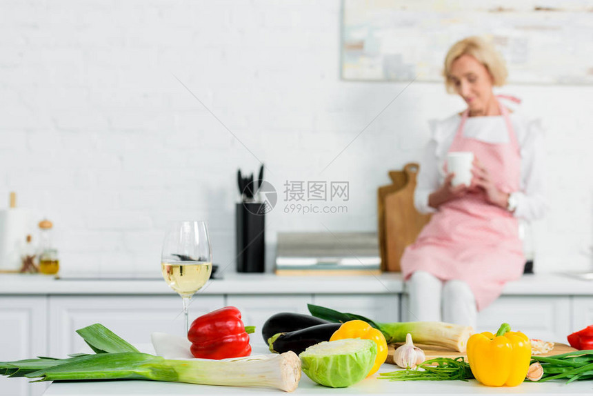 坐在厨房柜台上的美丽的高夫人茶杯和蔬菜放图片
