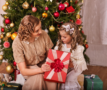 孩子妈在圣诞树附近接孩子妈给女儿带红弓的礼物图片