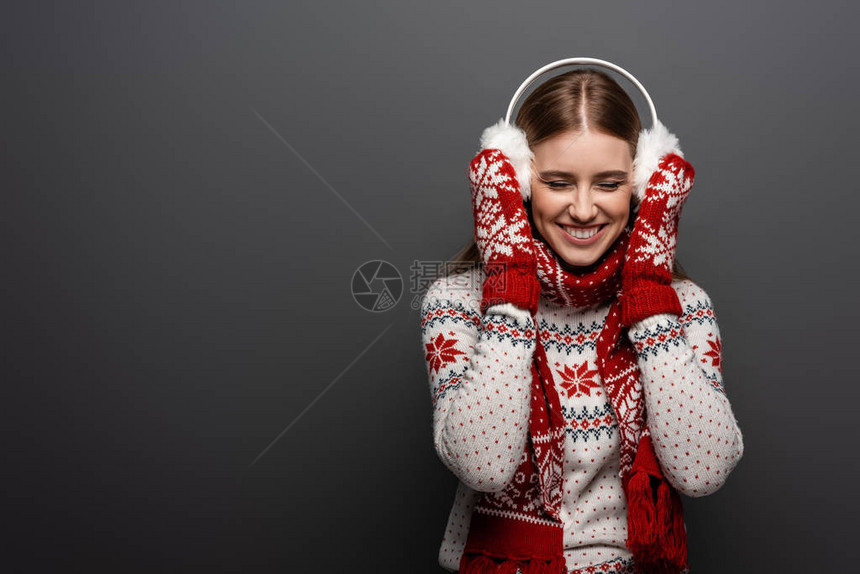 穿着圣诞毛衣围巾手套和耳膜的有吸引力的笑着妇女图片