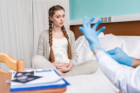 惊讶的孕妇坐在病床上看着戴医图片