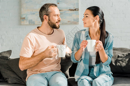 丈夫和妻子坐在沙发上喝咖啡图片