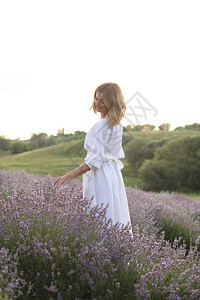 穿着白裙子的有色女子在紫衣花草田中行图片