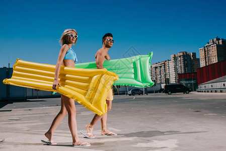 穿着海滩服装有充气床的年轻夫妇图片