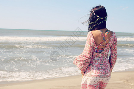美丽的女人穿着束腰外衣面朝大海背景图片