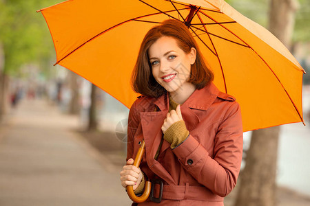 下雨天在户外打伞的漂亮年轻女子图片