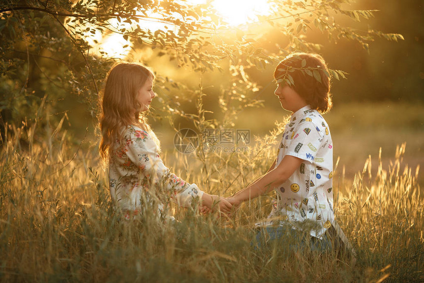女孩和男孩子在日落时坐在草地上看着对方图片