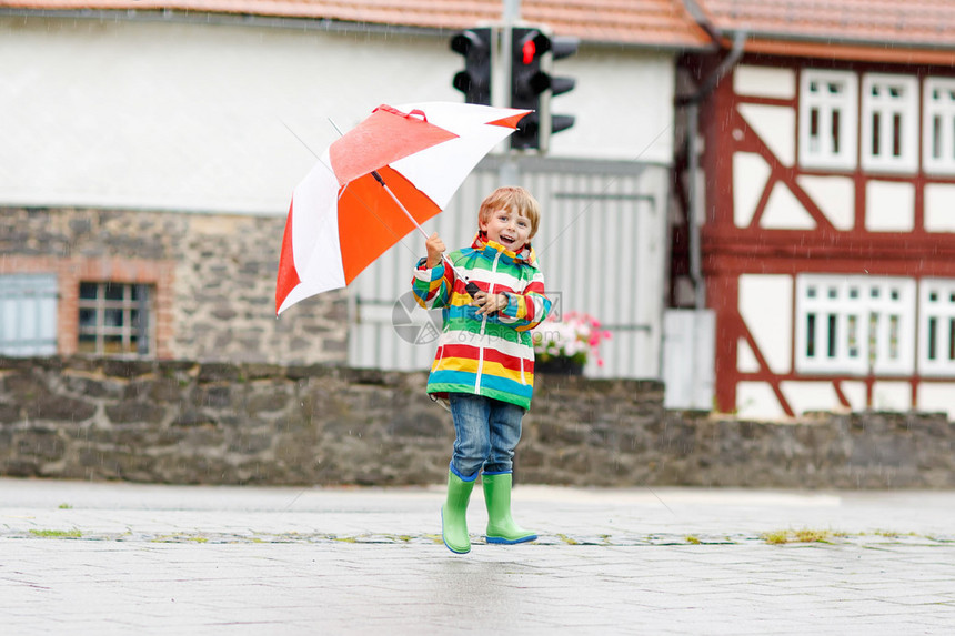 有趣的小男孩对下雨很满意跳舞和在街上图片