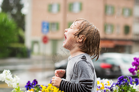 可爱的小男孩在户外的雨下玩耍在图片