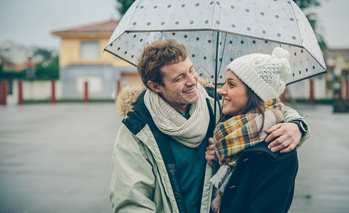 年轻美丽的夫妇在秋天的雨天在雨伞下拥抱和大笑的画像爱情和夫图片