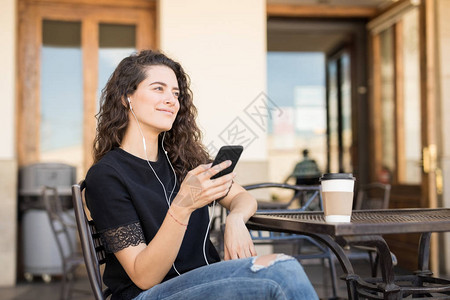 美丽的年轻女子在户外咖啡店放松背景图片