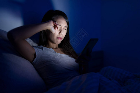 妇女晚上在床上使用手机头疼图片