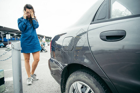 站在汽车旁边的悲伤女人在停车和电话旁说图片