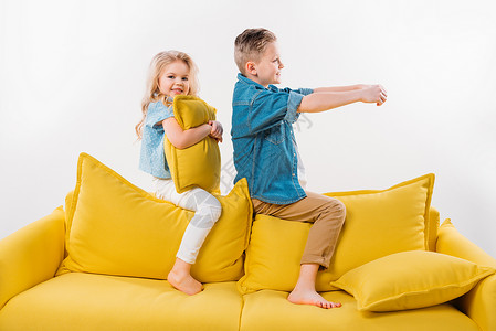男孩和妹坐在黄色沙发上假装是司机图片