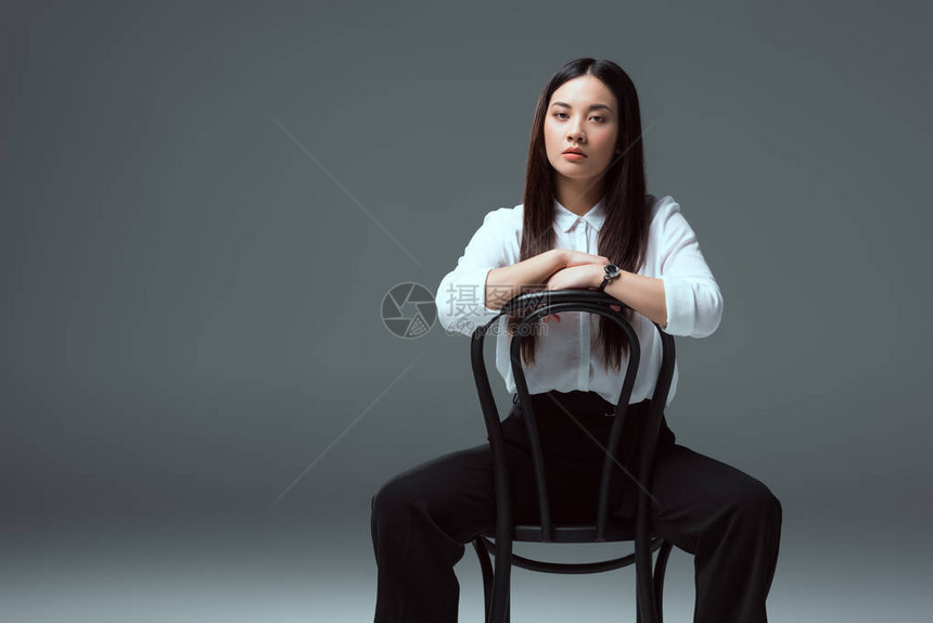 美丽的亚洲女孩坐在椅子上看着图片