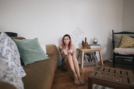 美丽的柔美女孩拿着一杯咖啡坐在公寓的地板图片