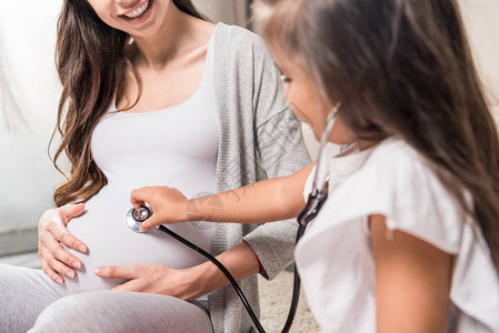 小女孩通过听诊器听到她怀孕母亲的肚子里的声音图片