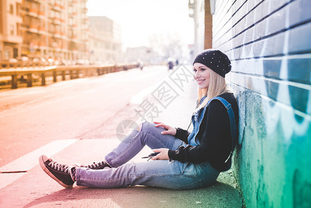 城市里年轻漂亮的金发直女人坐在地上图片