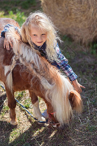 青春期前的孩子在农场拥抱可爱的小马图片