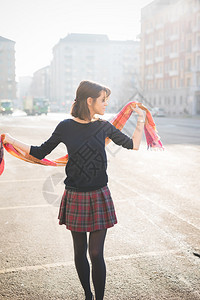 穿着彩色围巾在城市街道上玩和跳舞的女棕发美女露脸打扮成图片