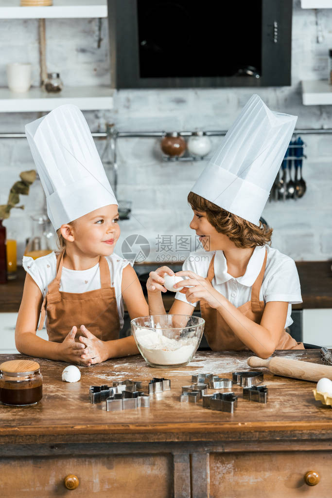 穿着围裙和厨帽的可爱孩子为饼干准备面团图片