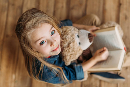 泰迪熊拿着书的小女孩的俯视图教图片