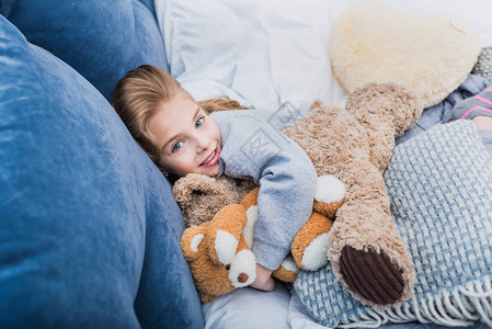 可爱的小女孩躺在床上带着泰迪熊躺在床上图片